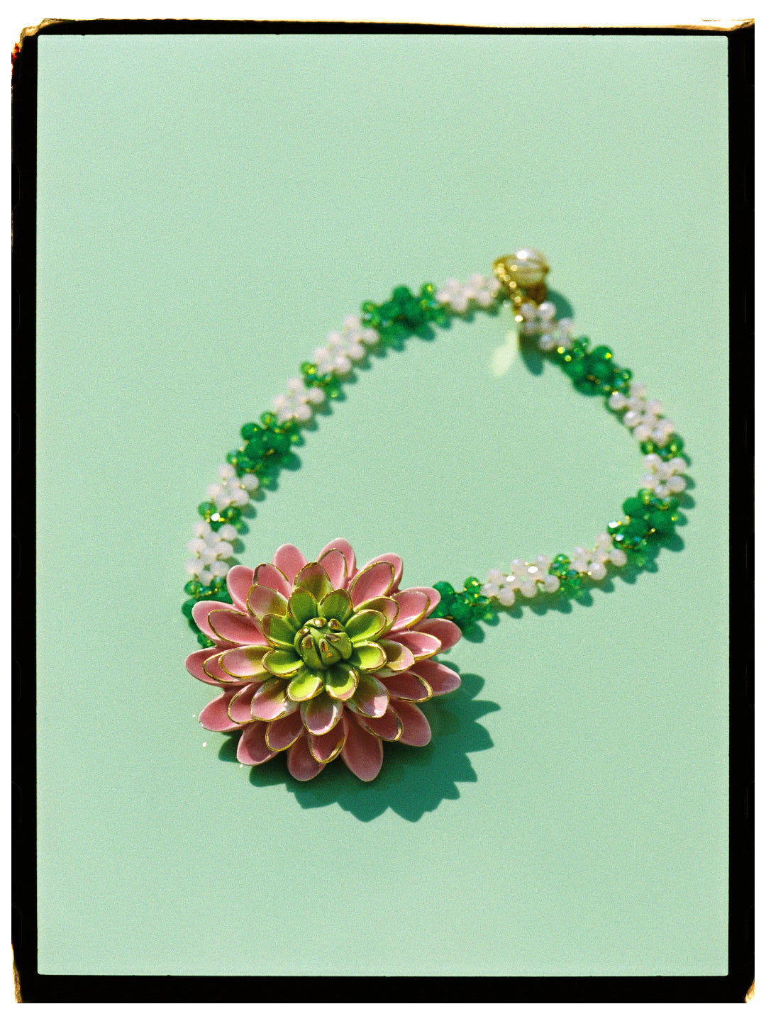 MATILDE, COLLAR DE CADENA TRENZADA CON HILO DORADO EN TONOS ROSA Y VERDE CON COLGANTE DE FLOR ROSA Y VERDE.