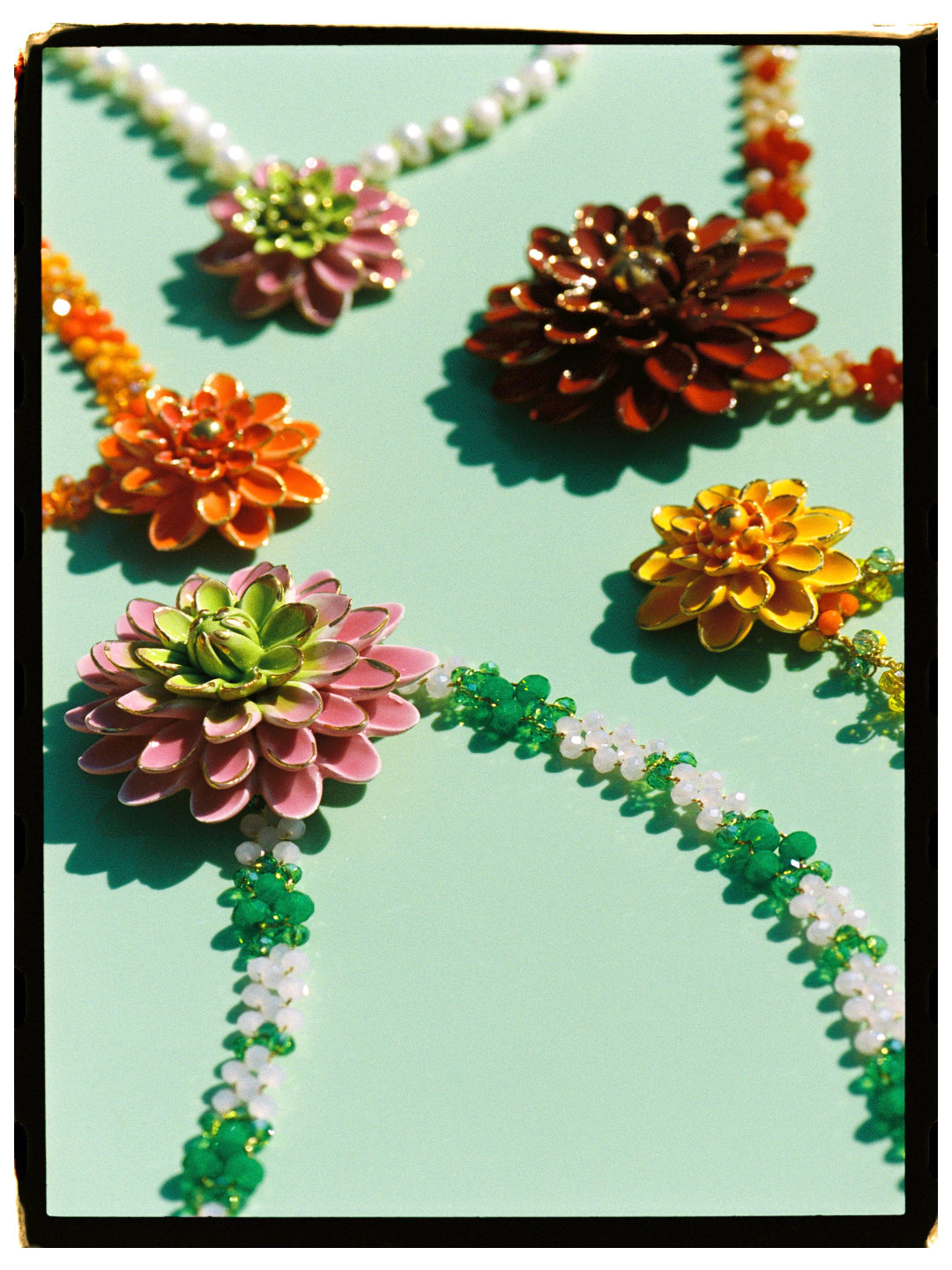 MATILDE, COLLAR DE CADENA TRENZADA CON HILO DORADO EN TONOS ROSA Y VERDE CON COLGANTE DE FLOR ROSA Y VERDE.